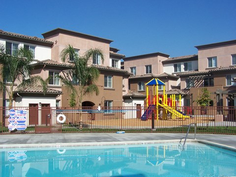 a swimming pool in front of apartments with a playground